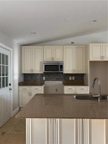 a kitchen with granite countertop a sink a stove a microwave and cabinets