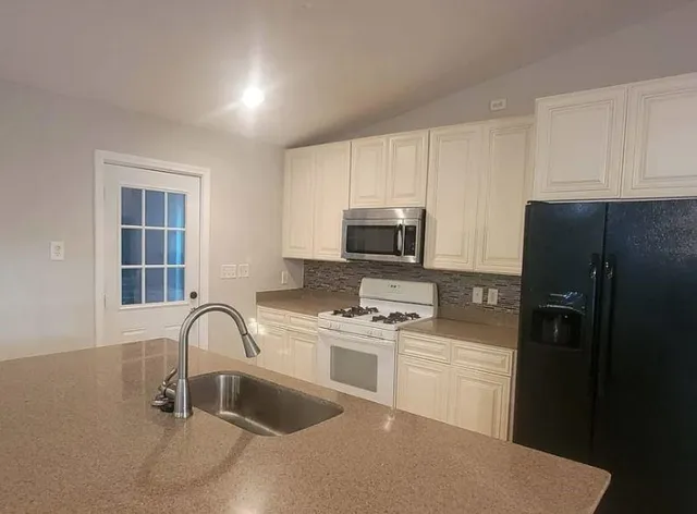 a kitchen with a refrigerator sink and white cabinets