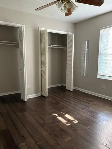 an empty room with wooden floor chandelier fan and windows