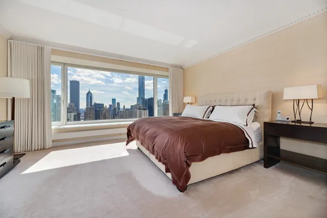a spacious bedroom with a bed lamp and a large window