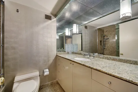 a bathroom with a granite countertop sink a toilet and a mirror