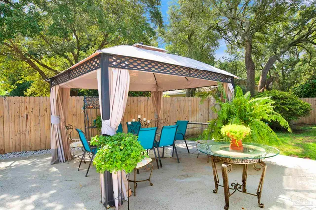 a backyard of a house with table and chairs under an umbrella