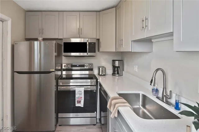 a kitchen with refrigerator a microwave a sink and cabinets