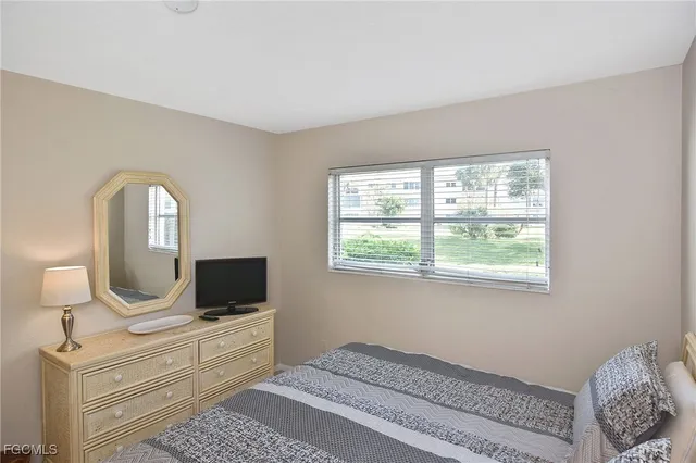 a bedroom with a bed a mirror on dresser and a window