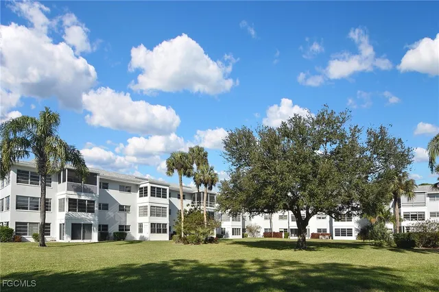 a view of a building with a big yard and large trees