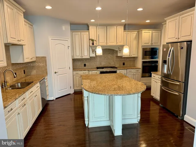 a kitchen with stainless steel appliances granite countertop a sink refrigerator and cabinets