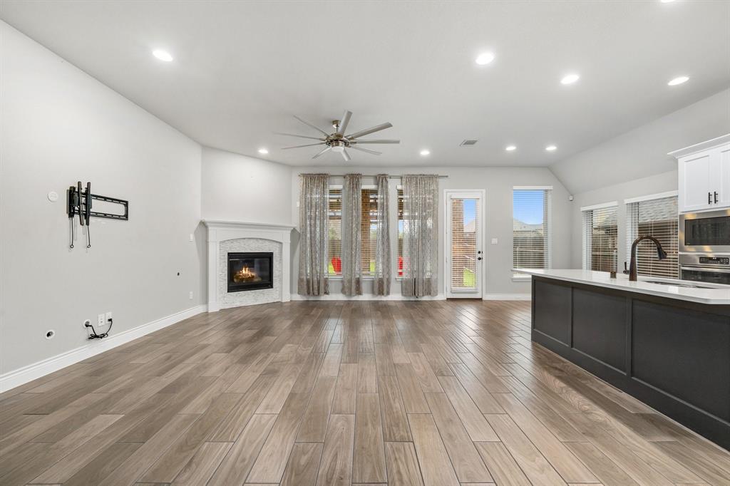 1501 Calcot Lane Forney, TX 75126 - Photo 5 of 34 Open-concept living space with wood-finish flooring, a corner fireplace with white mantel, recessed lighting, and a ceiling fan