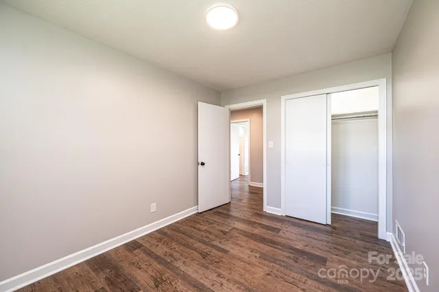a view of an empty room with wooden floor and closet