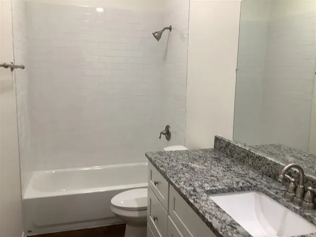 a bathroom with a granite countertop toilet sink and mirror