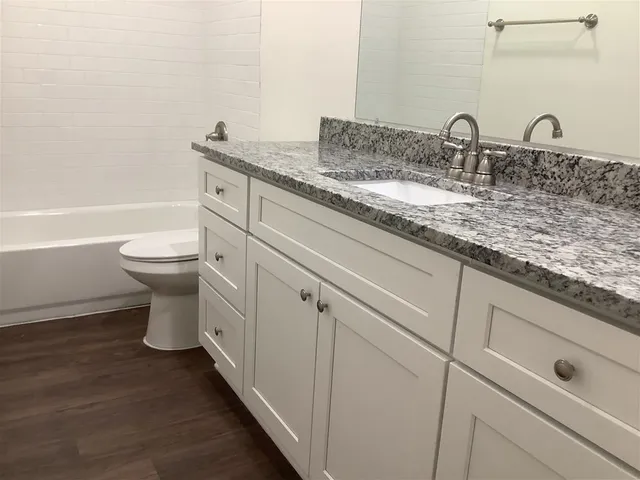 a bathroom with a granite countertop toilet sink and mirror