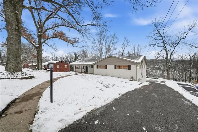 a front view of a house with trees and snow