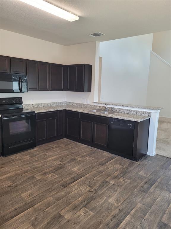 14917 Gypsum Mill Road Manor, TX 78653 - Photo 8 of 28 A well-appointed kitchen features dark wood cabinetry, granite counters, and a full suite of black appliances.