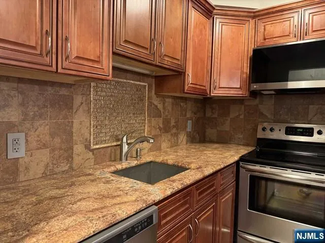 a kitchen with granite countertop a sink a stove and microwave