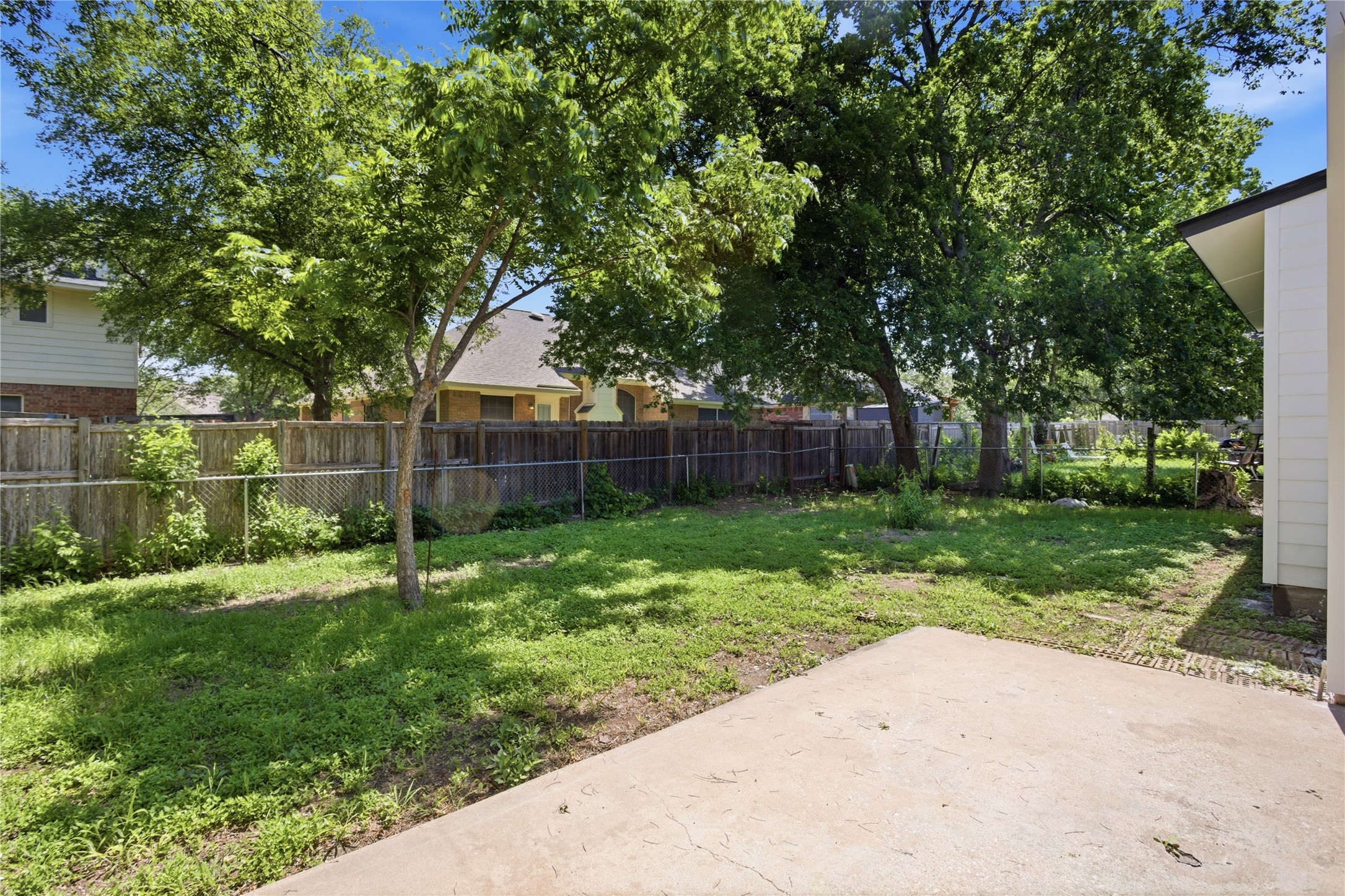 2110 Magazine Street Austin, TX 78727 - Photo 27 of 31 Concrete patio area opening to a fenced rear yard with mature trees and established greenery