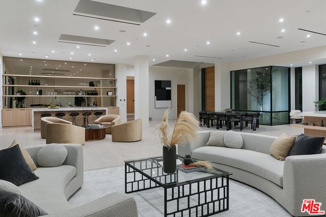 a living room with furniture kitchen view and a chandelier