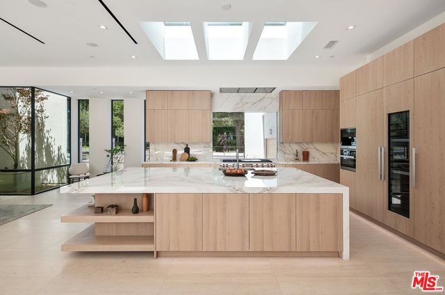 a large kitchen with kitchen island a sink counter space a large window and stainless steel appliances