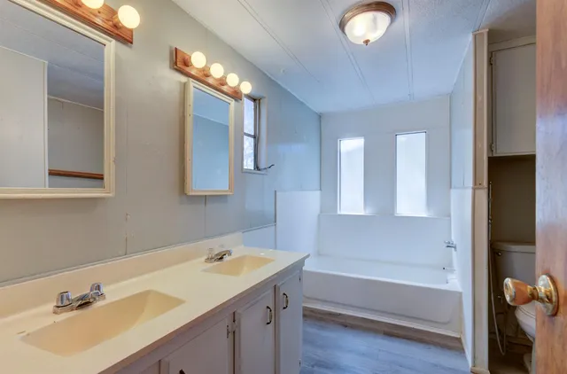 a bathroom with a tub sink and mirror