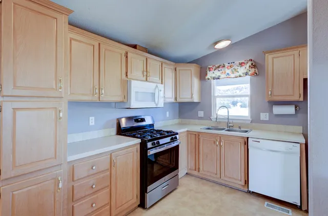 a kitchen with granite countertop white cabinets and white appliances
