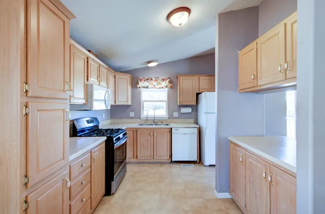 a kitchen with granite countertop a sink stove refrigerator and cabinets
