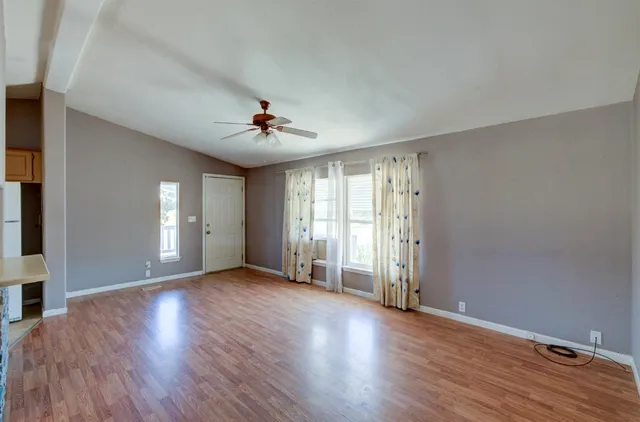 a view of an empty room with window and wooden floor