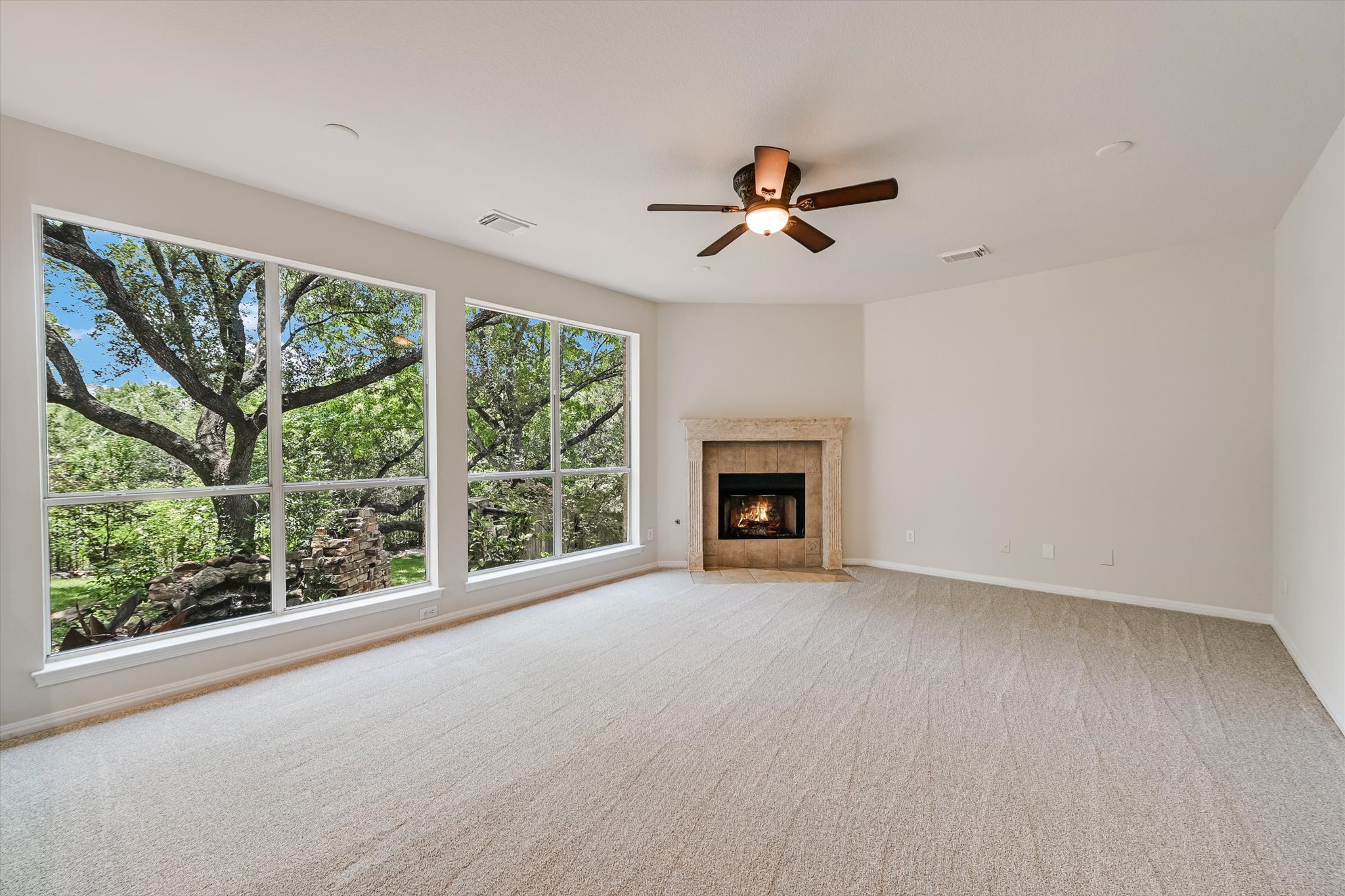 2849 Grimes Ranch Road Austin, TX 78732 - Photo 7 of 31 A spacious living area with serene arboreal views through expansive windows and a cozy corner fireplace.
