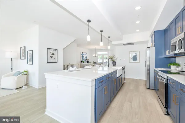 a large kitchen with stainless steel appliances kitchen island a large counter top a sink a stove and a refrigerator