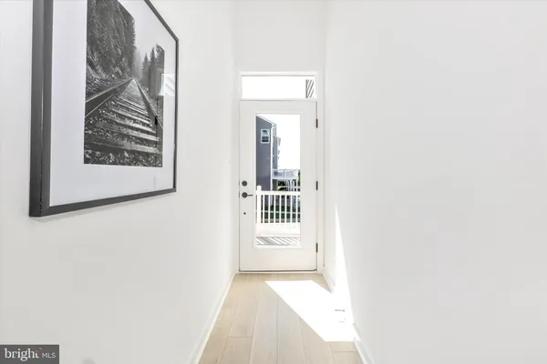 a view of a hallway with wooden floor and a bathroom