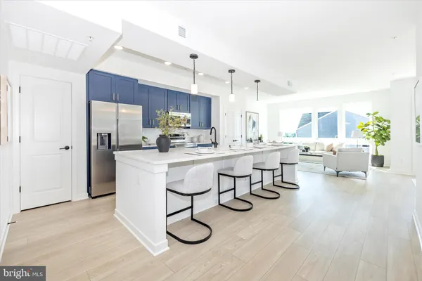 a living room with couches and kitchen view with wooden floor