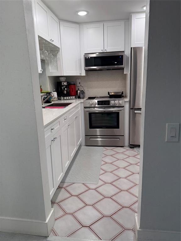 9360 Lime Bay Boulevard, Unit 202 Tamarac, FL 33321 - Photo 3 of 15 a kitchen with stainless steel appliances a stove a microwave and a refrigerator