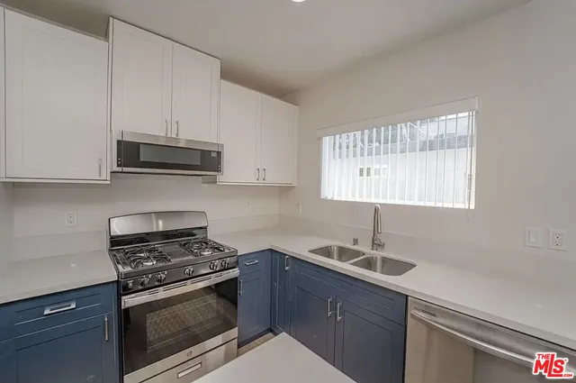 a kitchen with cabinets stainless steel appliances a sink and a stove