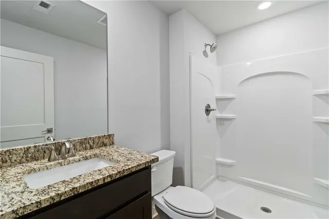 a bathroom with a granite countertop sink toilet and shower