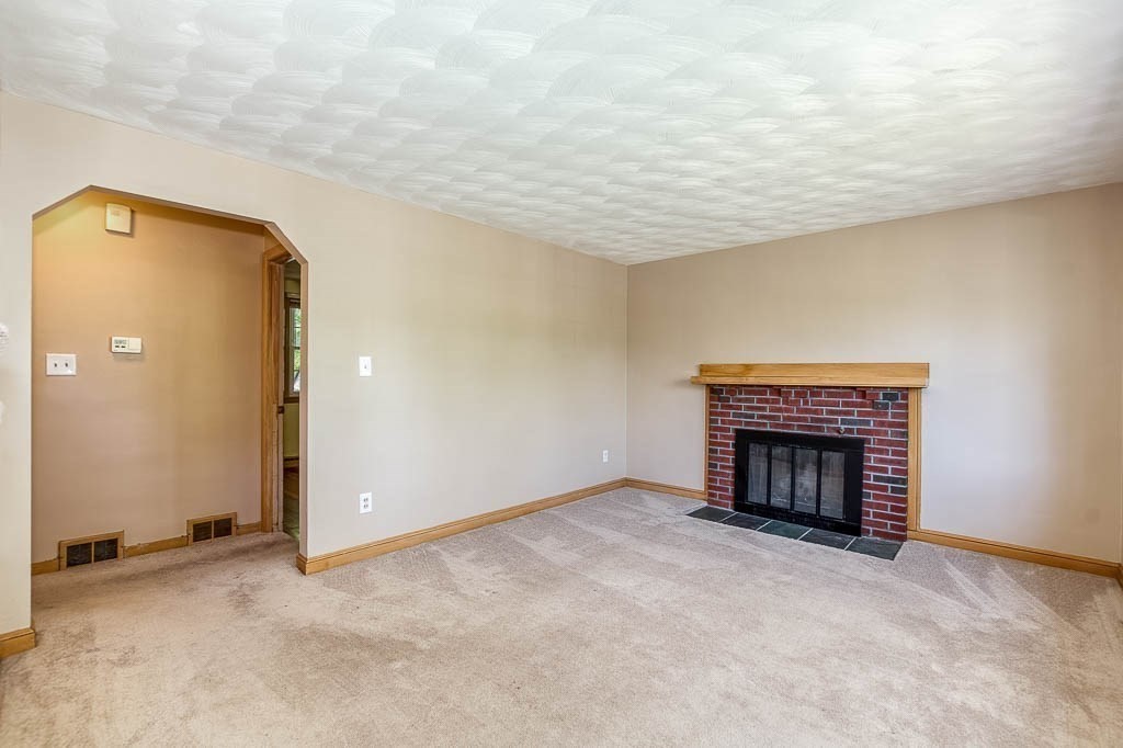 15 Locust Street Dedham, MA 02026 - Photo 6 of 38 an empty room with a fireplace and chandelier fan