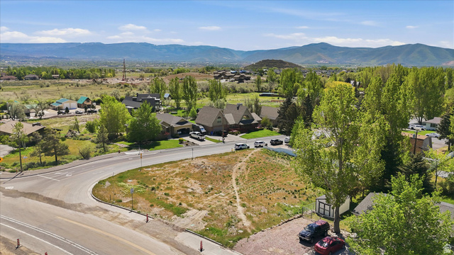 123 West 1050th North, Unit 41 Midway, UT 84049 - Photo 21 of 22 Expansive undeveloped lot presenting a prominent corner location with paved road frontage, mature trees, and mountainous terrain in the distant background