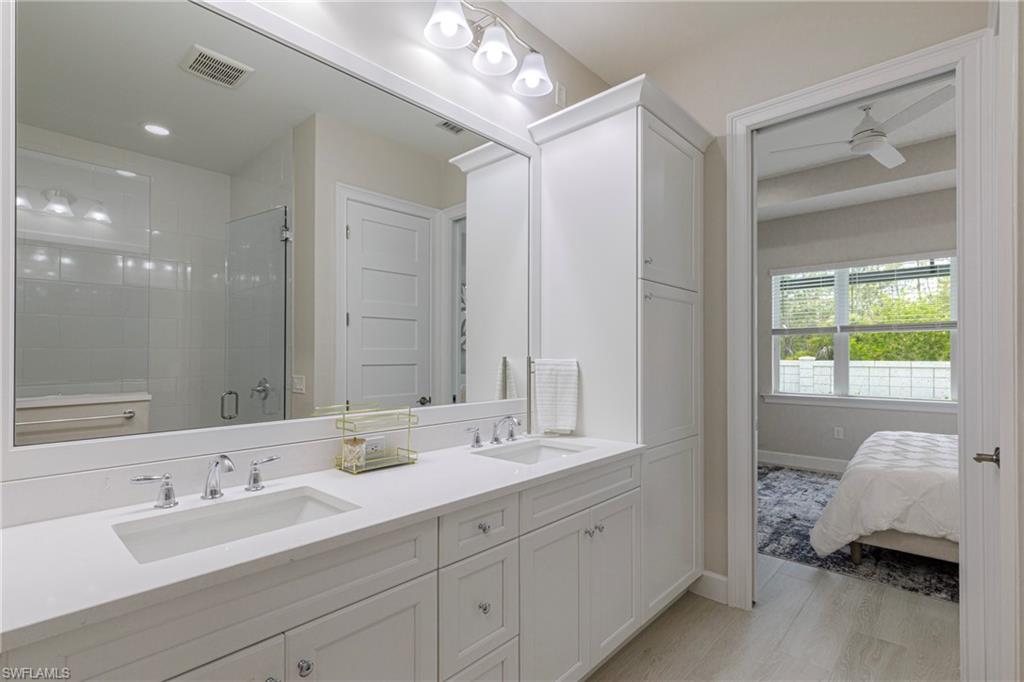 8909 Yucatan Court Naples, FL 34113 - Photo 11 of 36 Full bathroom with a shower stall, double vanity, ceiling fan, and light wood-style flooring