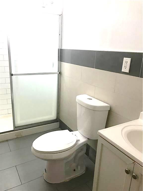 3519 Tryon Avenue Bronx, NY 10467 - Photo 3 of 4 Bathroom featuring stand up shower, vanity, tile walls, toilet and tile patterned floors