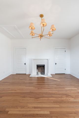 an empty room with wooden floor and fireplace