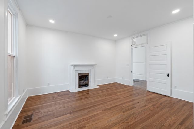 a view of a hallway with wooden floor and cabinet