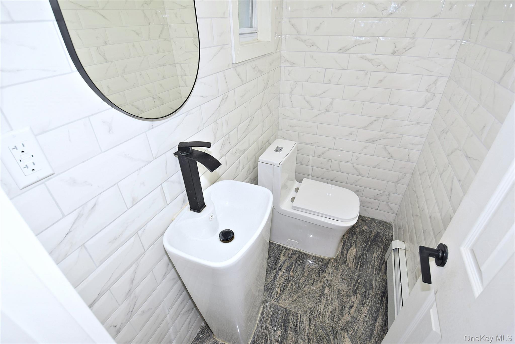 25 Old Mill Road Great Neck, NY 11023 - Photo 36 of 45 Half bath with window. White subway tile walls with subtle veining, modern pedestal sink with matte black faucet, and a contemporary toilet