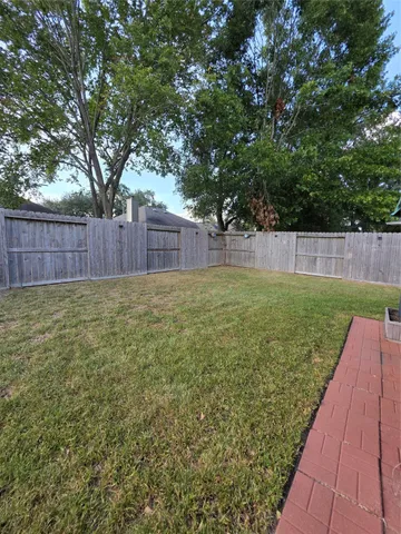 a view of a backyard with a large tree and wooden fence