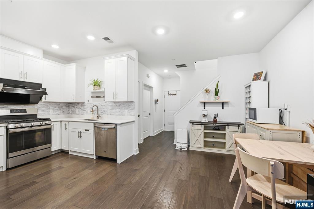 385 Main Street Little Falls, NJ 07424 - Photo 6 of 42 a kitchen with stainless steel appliances a stove a sink a oven a dining table and chairs