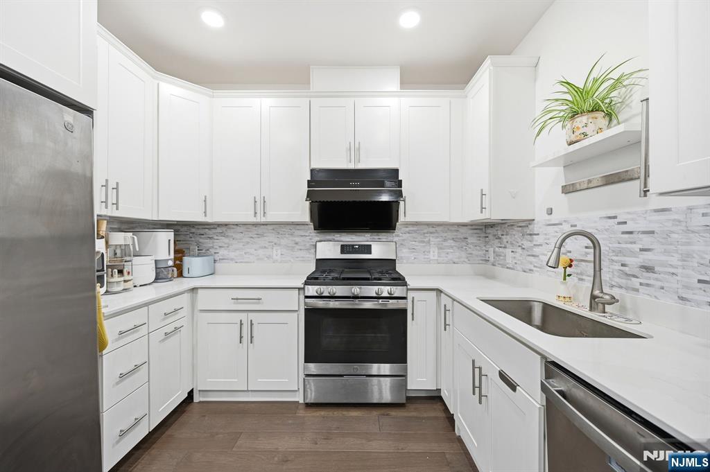 385 Main Street Little Falls, NJ 07424 - Photo 8 of 42 a kitchen with stainless steel appliances a stove a sink a microwave and cabinets