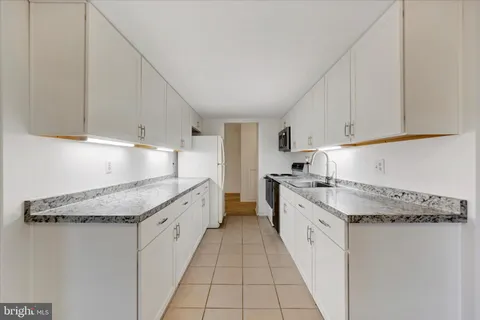 a kitchen with granite countertop white cabinets and white appliances