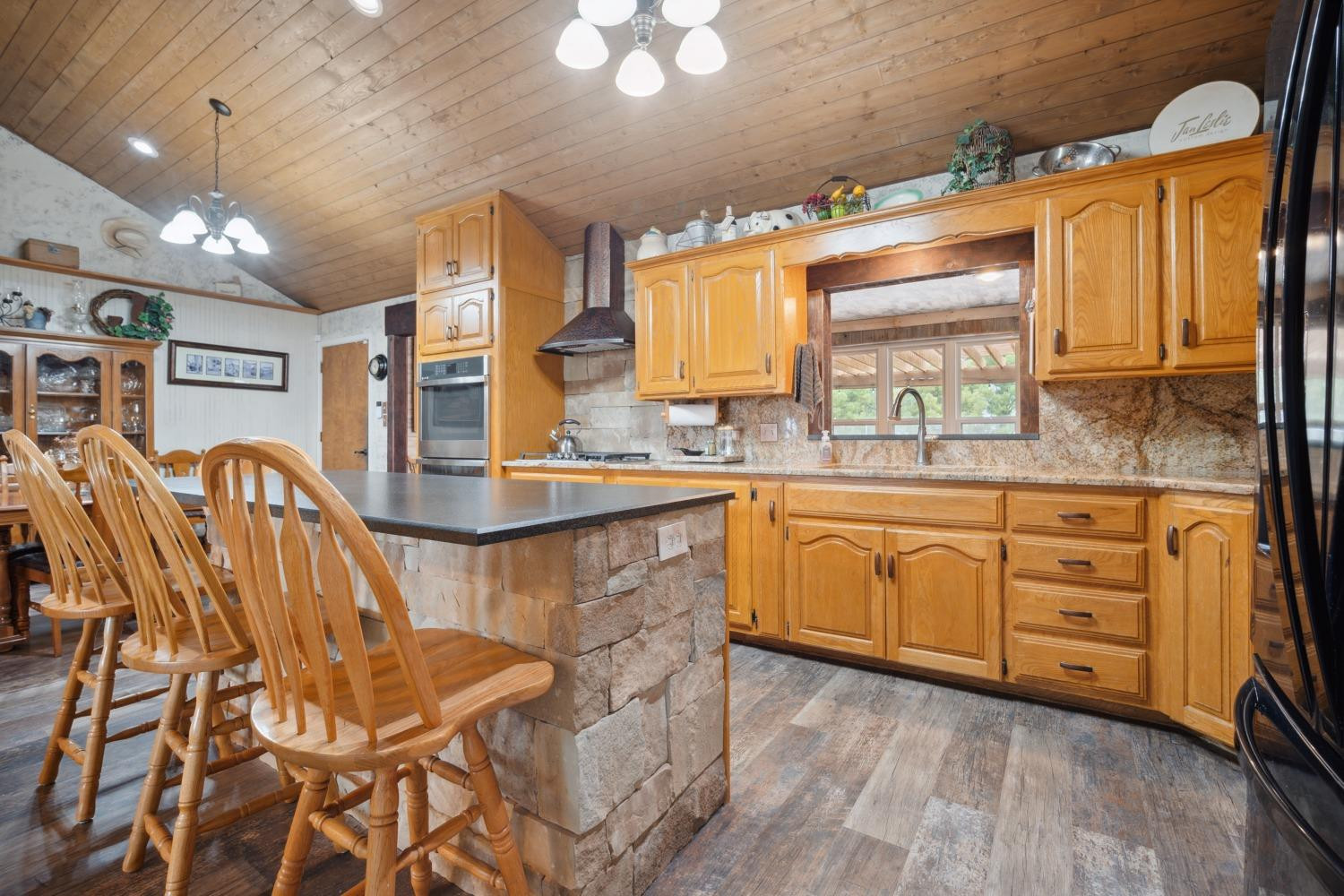 9002 Woodrow Road Wolfforth, TX 79382 - Photo 9 of 48 a kitchen with stainless steel appliances kitchen island granite countertop a table chairs and a wooden cabinets