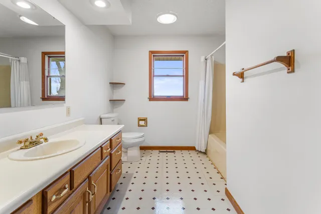 a bathroom with a sink a toilet a shower and a window