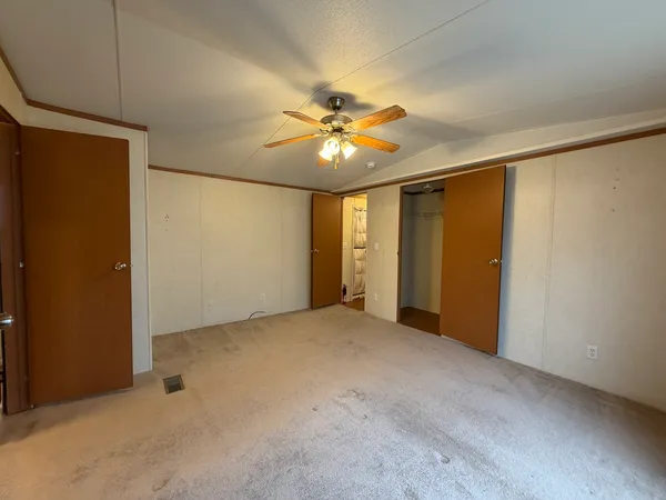 an empty room with closet and a ceiling fan