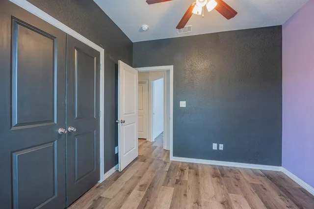 a view of a hallway with wooden floor and a bathroom