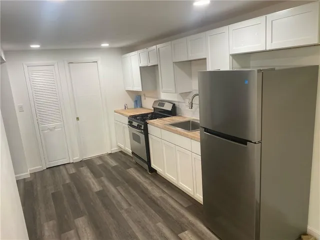 a kitchen with a refrigerator a stove and white cabinets