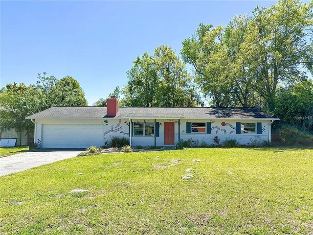 a front view of house with yard and trees in the background