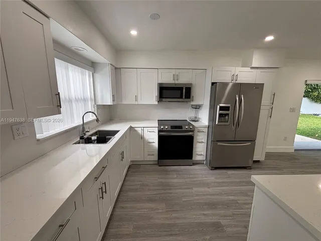 a large kitchen with stainless steel appliances granite countertop a sink a stove and a refrigerator