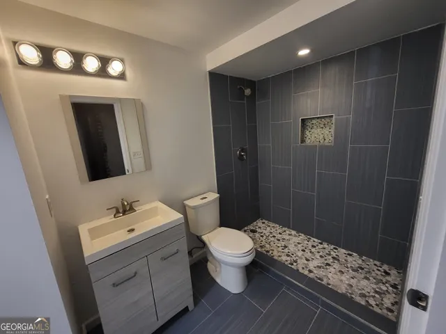 a bathroom with a sink a toilet a shower and a mirror